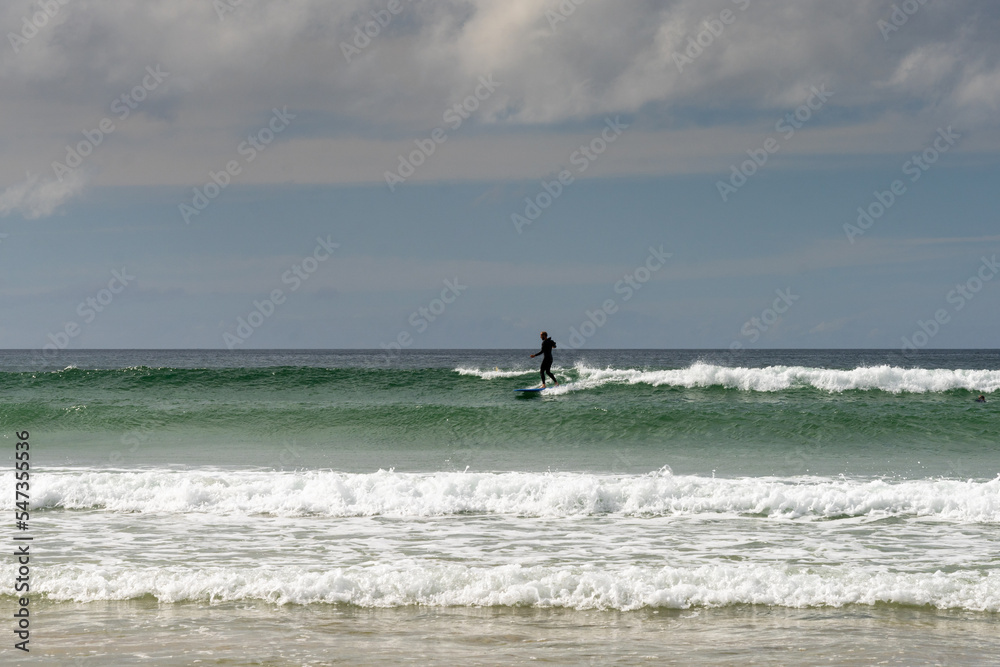 surfer catching a wave at Fistral Beach in Newquay surfer catching a wave at Fistral Beach in Newquay