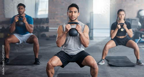 Fitness, workout and kettlebell with a personal trainer in class with a group of students for exercise. Portrait, gym and strong with a coach weight training a man and woman athlete in a sports club