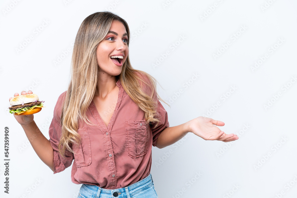 Obraz premium Young pretty Uruguayan woman holding a burger isolated on white background with surprise facial expression