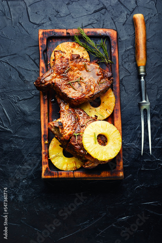 Barbecue steak with pineapples on cutting board