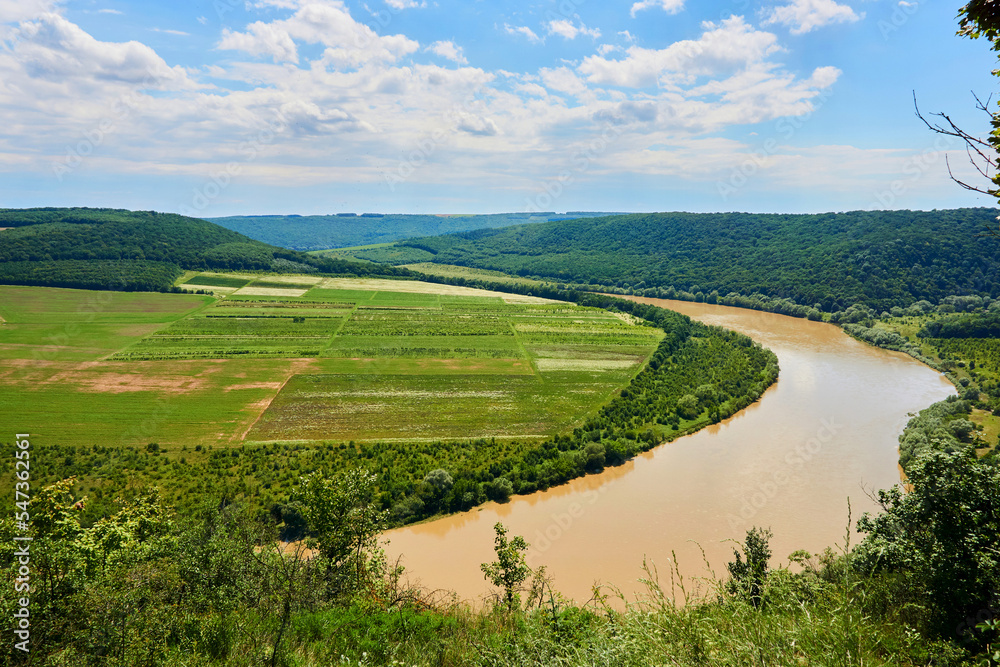 Summer river flowing among green hills and fields. Tovtry National Park Ukraine