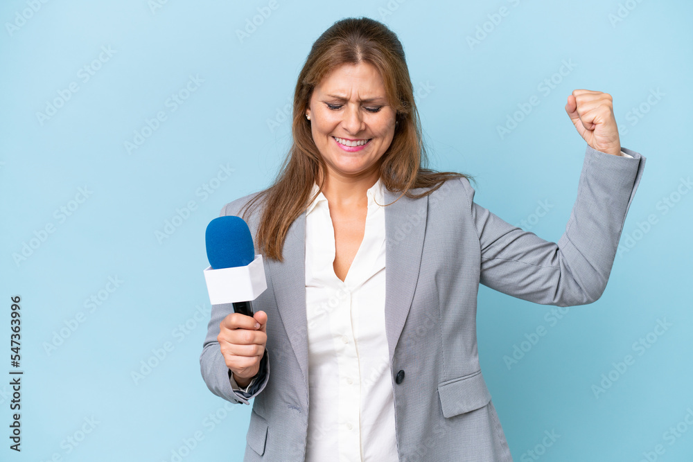 Middle-aged TV presenter woman over isolated blue background doing strong gesture Middle-aged TV presenter woman over isolated blue background doing strong gesture