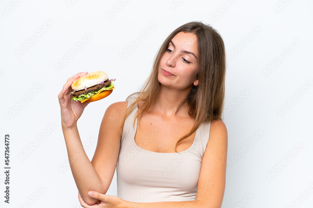 Young pretty woman holding a burger isolated on white background with sad expression