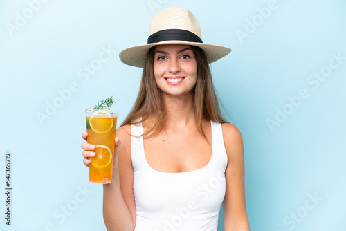 Young beautiful woman holding a cocktail isolated on blue background smiling a lot