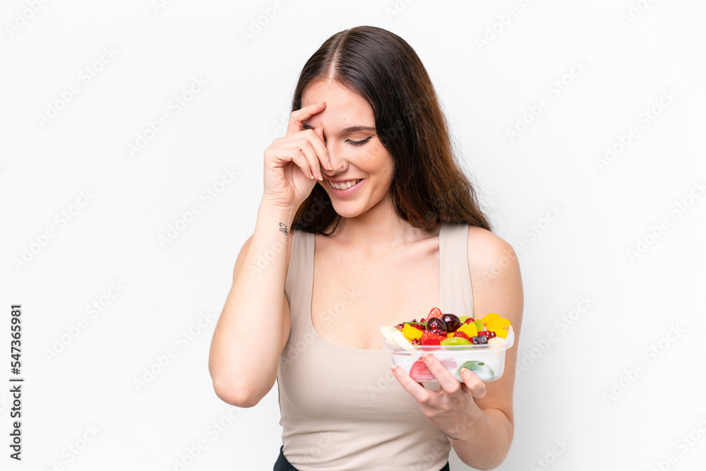 Young caucasian woman holding a bowl of fruit isolated on white background laughing Young caucasian woman holding a bowl of fruit isolated on white background laughing