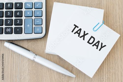 tax day inscription on the card on the table next to the pen and calculator, business concept