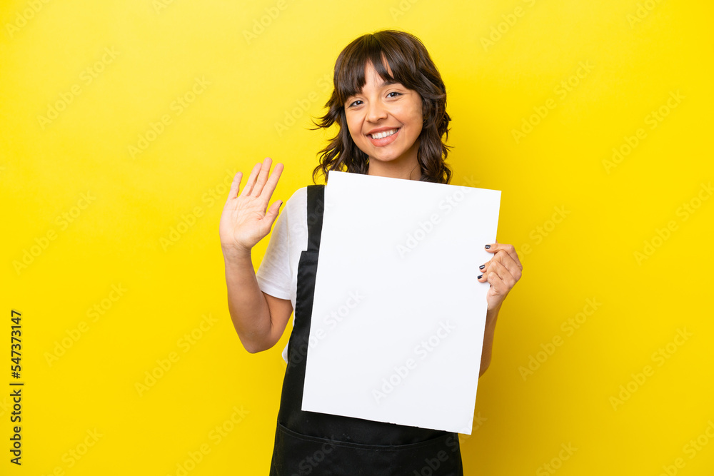 Restaurant waiter latin woman isolated on yellow bakcground holding an empty placard and saluting Restaurant waiter latin woman isolated on yellow bakcground holding an empty placard and saluting