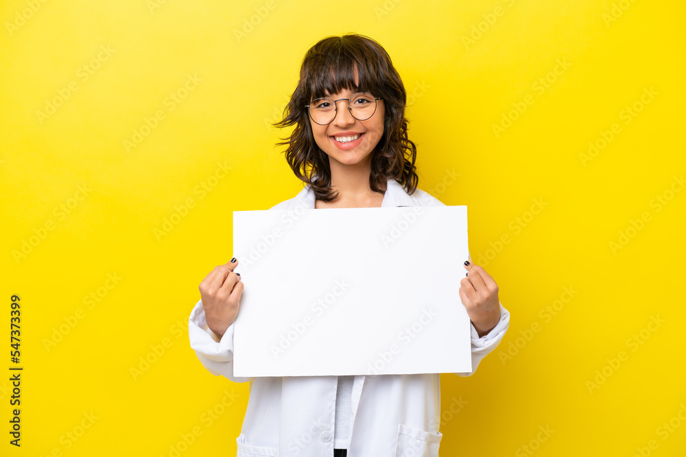 Young doctor latin woman isolated on yellow background holding an empty placard with happy expression Young doctor latin woman isolated on yellow background holding an empty placard with happy expression