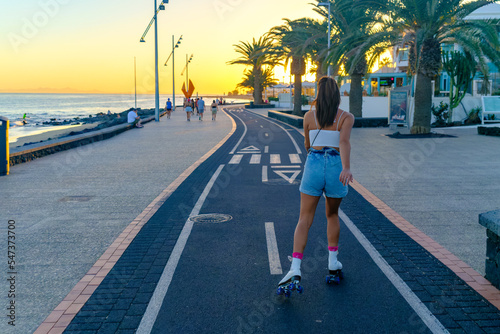 Young adult girl skating along the bike path on the beach boardwalk. Puerto del Carmen  Lanzarote  Canary Islands  Spain