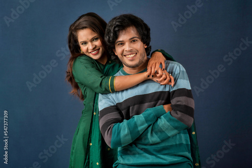 Portrait of a happy cheerful young couple posing on dark background. Attractive man and woman being playful.