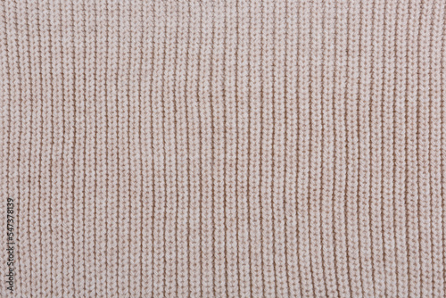 Texture of beige knitted woolen fabric, close-up