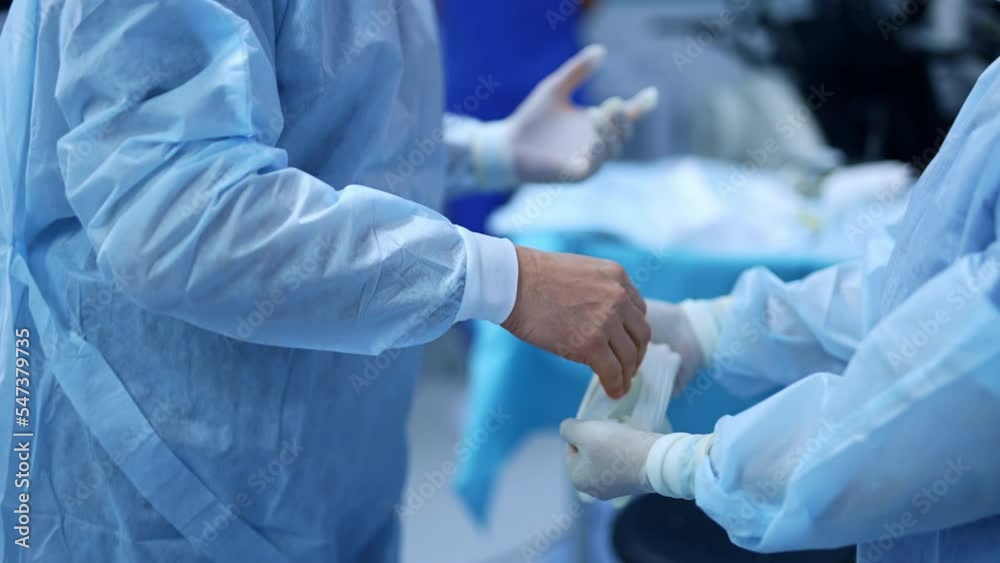 Nurse holding the gloves for the surgeon to wear them. The doctor is dressed for the surgery operation in modern clinics. Nurse holding the gloves for the surgeon to wear them. The doctor is dressed for the surgery operation in modern clinics.