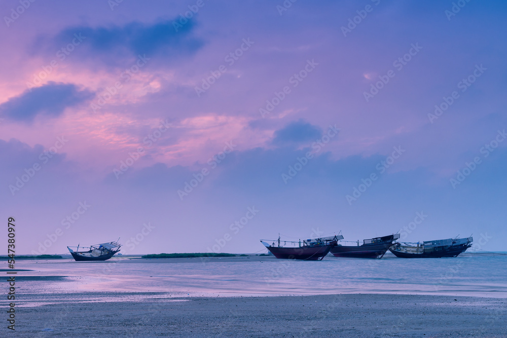 Boats at sea coast during sunset.