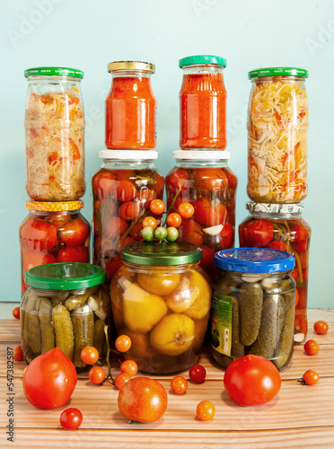 From the winter stocks of home canning cucumbers, figs, chopped white cabbage and ketchup, in glass jars on a blue background.