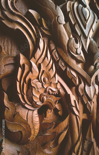 Side view of wood carving Kranok with serpent traditional pattern on teak wooden door background in Wat Krok Krak temple at Samut Sakhon, Thailand