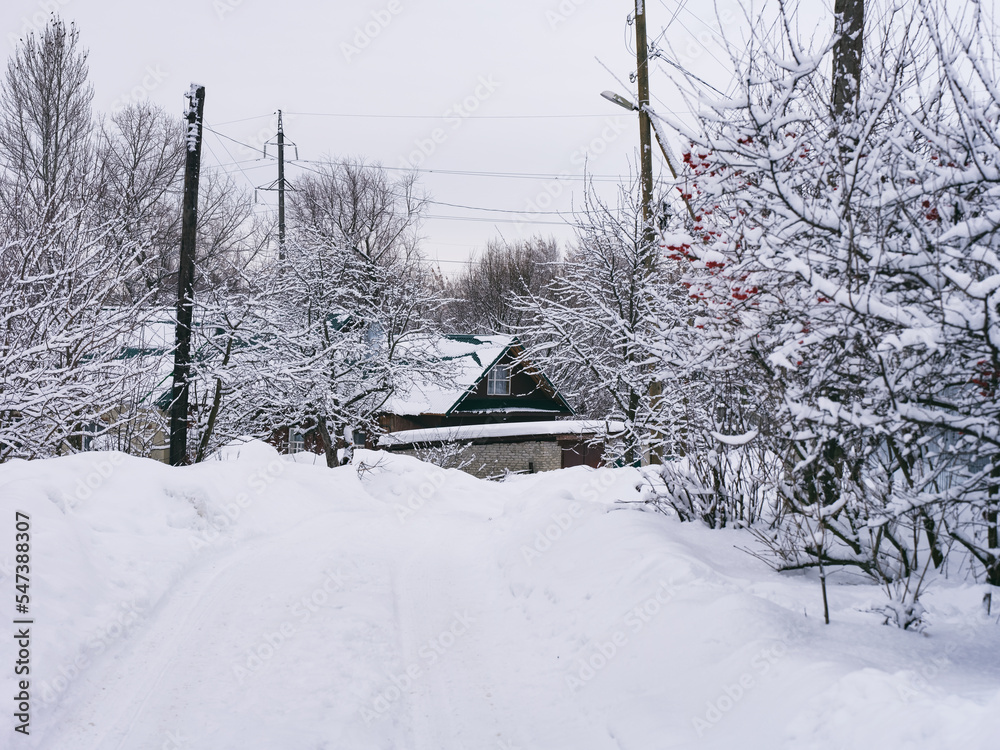 A road covered in snow. There is a house in the background, which the road is leading to A road covered in snow. There is a house in the background, which the road is leading to