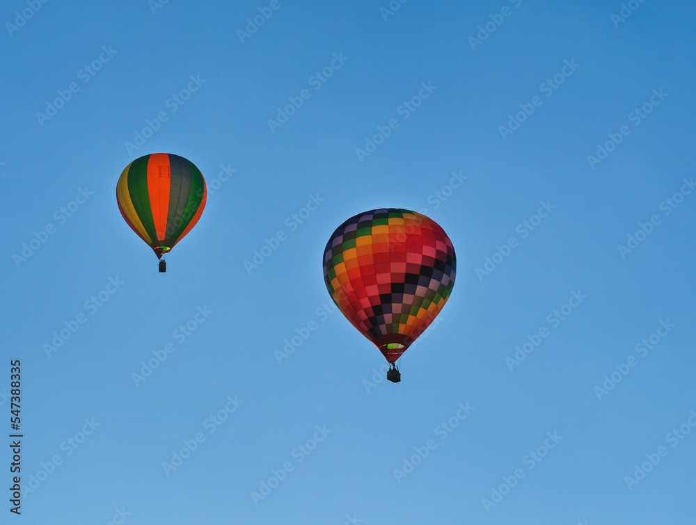 Two colorful hot air balloons flying through the sky.