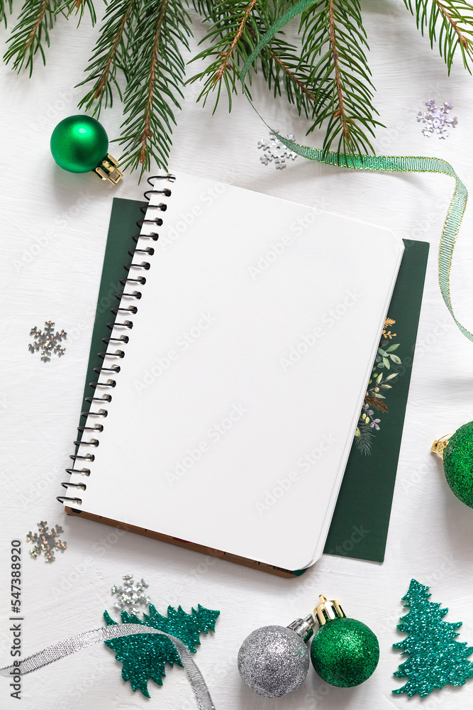 Christmas festive composition with empthy notebook, Christmas green decor, fir tree branches on a green background. Copy space. Christmas festive composition with empthy notebook, Christmas green decor, fir tree branches on a green background. Copy space.