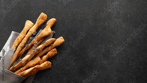 Crispy breadsticks with parmesan and lavender, grissini, on black stone background, top view, place for text, banner