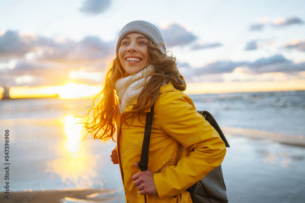 Happy tourist in a yellow jacket posing by the sea at sunset. Travelling, lifestyle, adventure. Happy tourist in a yellow jacket posing by the sea at sunset. Travelling, lifestyle, adventure.