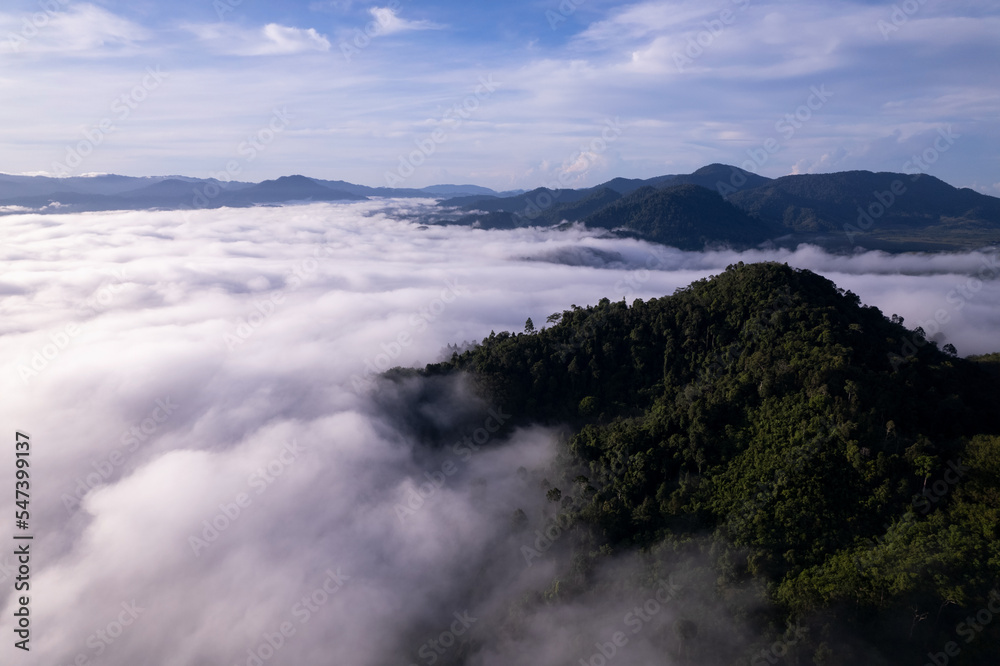 Aerial view of flowing fog waves on mountain tropical rainforest,Bird eye view image over the clouds Amazing nature background with clouds and mountain peaks in Thailand