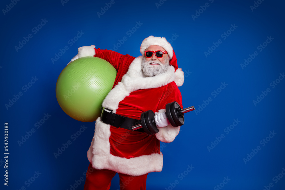 Photo of handsome strong santa claus wear red costume hat dark holding fitball building muscles isolated red color background
