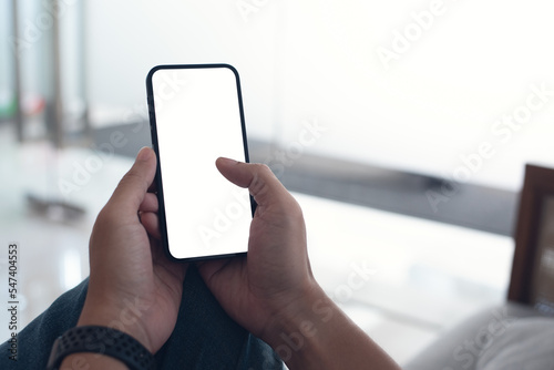 Mobile phone mockup for advertising. Mock up image of man hand holding and using smartphone with blank screen for mobile app design or text advertisement © tippapatt