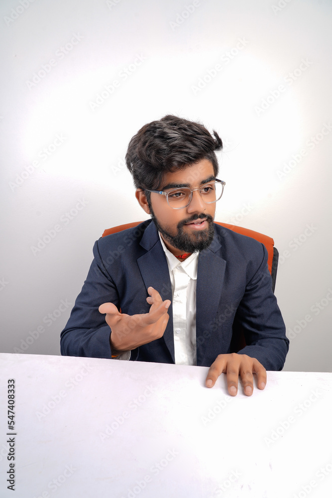 indian young business man on chair table talking to someone or explaining something to someone indian young business man on chair table talking to someone or explaining something to someone