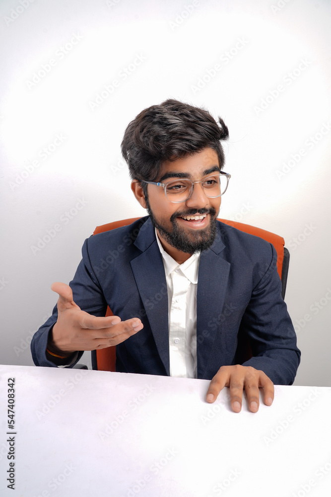 indian young business man on chair table talking to someone or explaining something to someone indian young business man on chair table talking to someone or explaining something to someone