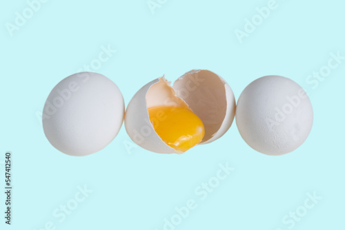 White eggs and egg yolk in shell isolate on turquoise background