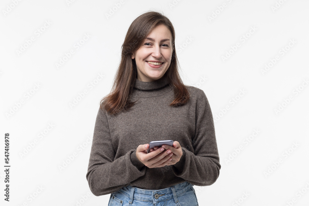 Portrait of a positive cheerful girl using a smartphone on a white background. Amazing app.Share the news on social networks Portrait of a positive cheerful girl using a smartphone on a white background. Amazing app.Share the news on social networks