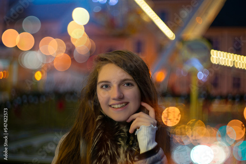 Girl in Christmas traditional market decorated with holiday lights in the evening. Beautiful night with blur lights and colors. Artistic photography with nice blured light bokeh.