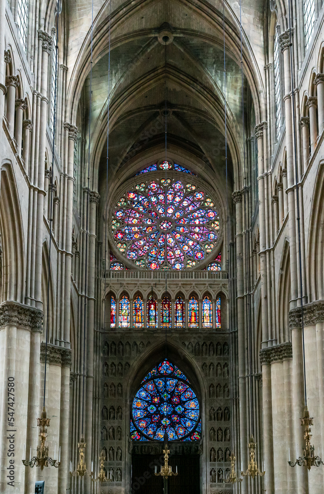 view of the reverse side of the West Facade of the Reims Cathedral with colorful stained glass windows and sculptures