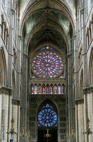 view of the reverse side of the West Facade of the Reims Cathedral with colorful stained glass windows and sculptures