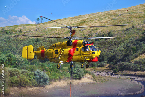 Helicóptero dos Bombeiros reabastece água para apagar incêndia florestal photo