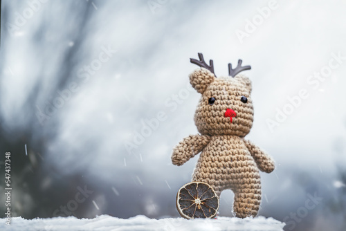 Leinwand Poster Portrait of a cute crocheted reindeer during the first snow of the year in a gar