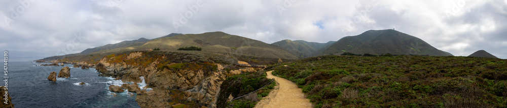 Panoramic view of cliffs, mountains, and path on the California coast