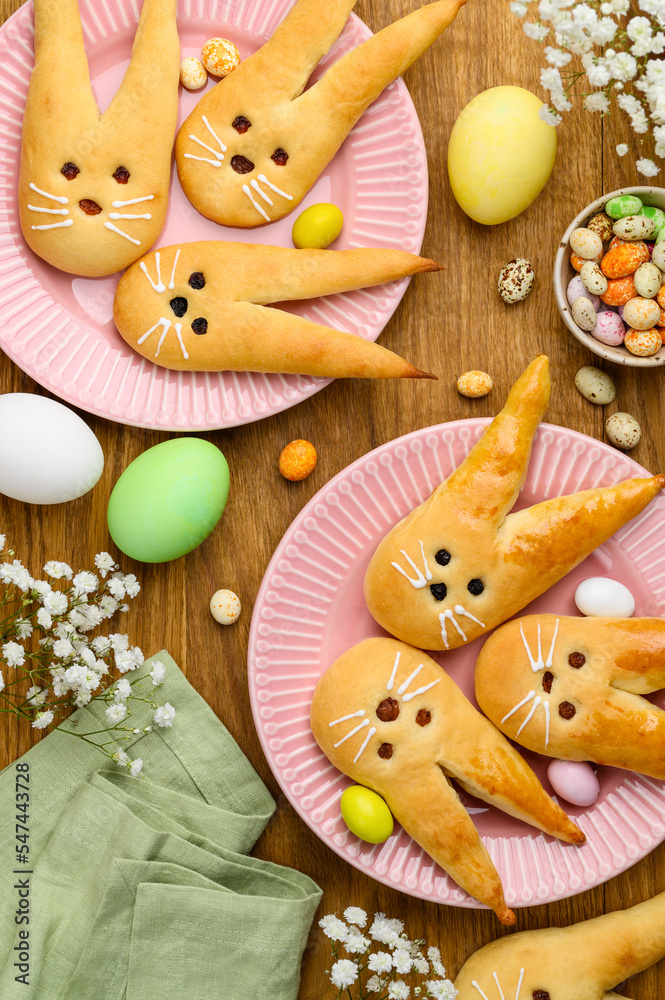 Easter bunny buns from yeast dough on a pink plates. Traditional Easter dessert rabbits, symbol, concept, decoration. Top view Easter bunny buns from yeast dough on a pink plates. Traditional Easter dessert rabbits, symbol, concept, decoration. Top view