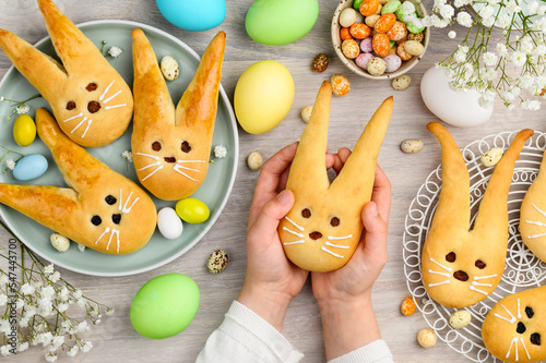 Easter bunny buns from yeast dough. Traditional Easter dessert rabbits, symbol, concept, decoration. Children's hands in the frame. Top view 