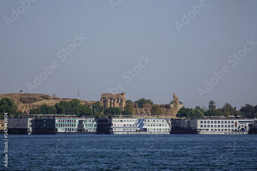 Kom Ombo, Egypt: Cruise ships lined up along the bank of the Nile River; the Kom Ombo Temple in the background.