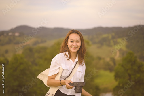 Happy smiling young woman traveller hand holding her camera