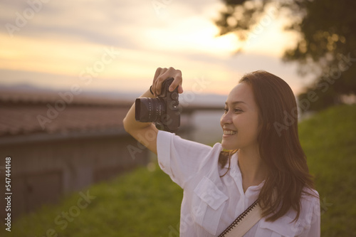 Happy young woman enjoy using camera in golden hour