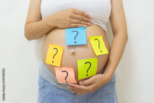 Close up pregnant woman with question marks on tummy, Concept of pregnancy, choosing baby name photo