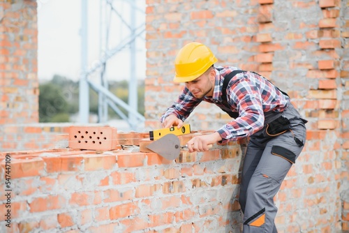 Foto construction mason worker bricklayer installing red brick with trowel putty knife outdoors