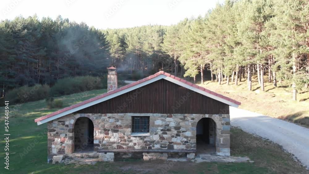Cinematic aerial shot of a drone flying while approaching a shelter with a burning fireplace in the middle of the forest backgrounds and videos of adventure and nature. Cinematic aerial shot of a drone flying while approaching a shelter with a burning fireplace in the middle of the forest backgrounds and videos of adventure and nature.