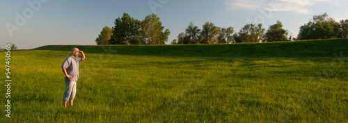 Obraz na plátně Young bald man standing on the spring meadow grass on a sunny day