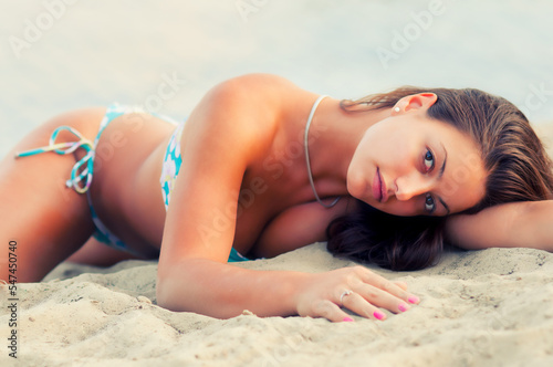 Young sexy woman in bikini sunbathing on the sea beach on a beautiful summer day
