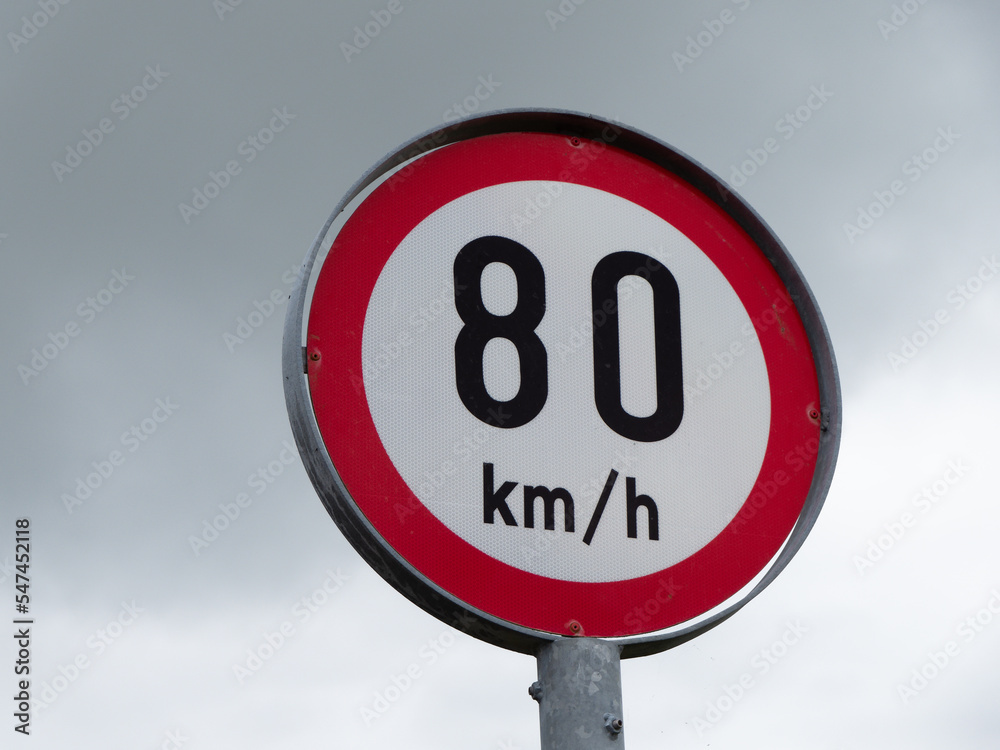 Round sign limiting speed on the background of a cloudy sky. Signs warning of a maximum speed of 80 km h Round sign limiting speed on the background of a cloudy sky. Signs warning of a maximum speed of 80 km h