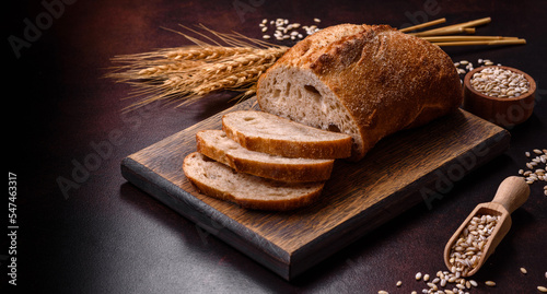 A loaf of brown bread with grains of cereals on a wooden cutting board