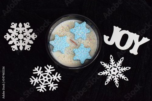 Holiday soy candle with blue snowflake molds, wood wick, joy, white snowflakes on black sweater with silver glitter. 